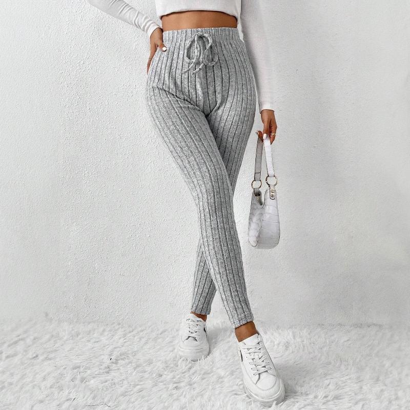 Damskie szare legginsy w prążki z wysokim stanem, stylizacja z białą bluzką i białymi sneakersami