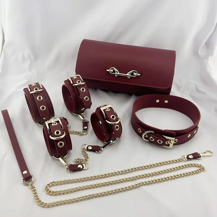 Bordowy zestaw skórzanych kajdanek, obroży i smyczy z metalowymi detalami na białym tle