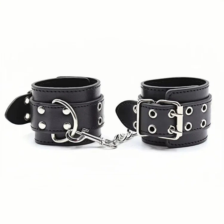 Czarne skórzane kajdanki z metalowymi nitami i srebrnym łańcuchem na białym tle