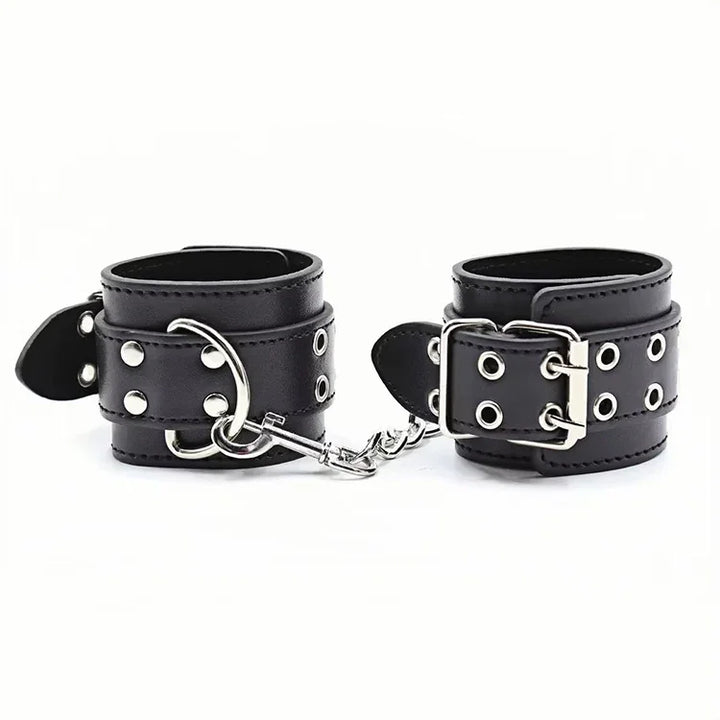 Czarne skórzane kajdanki z metalowymi nitami i srebrnym łańcuchem na białym tle