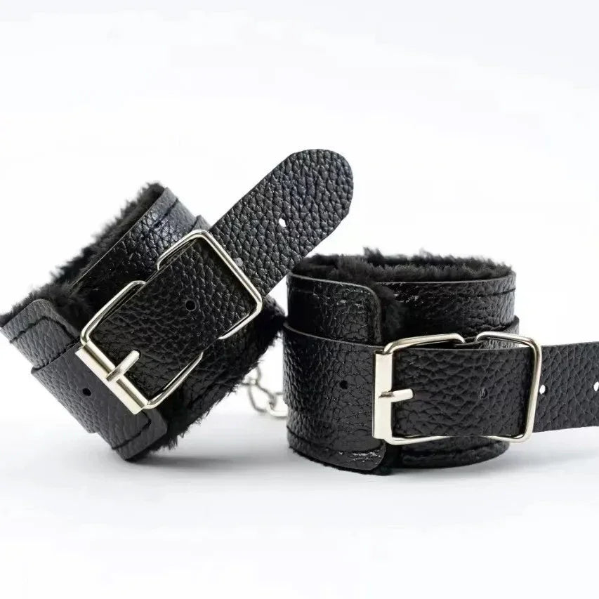 Czarne skórzane kajdanki z futrzanym wnętrzem i srebrnymi klamrami na białym tle